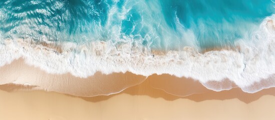 Fototapeta premium A stunning summer tropical background with beautiful sea waves seen from an aerial top view of beach sand providing ample copy space