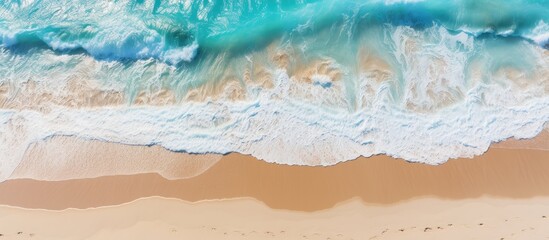 A stunning summer tropical background with beautiful sea waves seen from an aerial top view of beach sand providing ample copy space