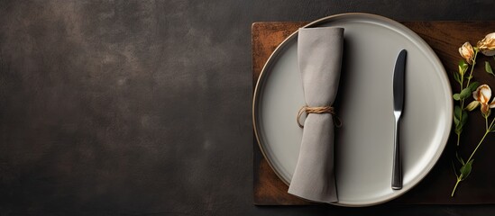 A top down view of a white craft plate cutlery and napkin arranged on a dark stone table This setting serves as a background for menus layouts and recipe texts creating a stylish and inviting food fl