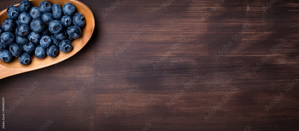 Poster a top down view of a fresh blueberry placed on a wooden spoon with the surrounding area left empty f