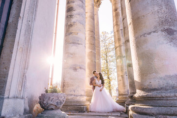 beautiful loving young couple among columns and sun rays posing outdoors.