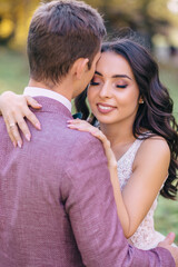 Beautiful wedding couple of newlyweds lovingly hugging on the background of nature