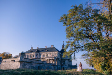 The newlyweds embrace near the ancient castle, Renaissance palaces. Photo session near the medieval castle.