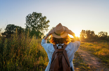 Portrait of a young cheerful woman in a hat walking in the countryside in summer