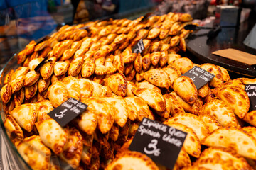 An empanada is a type of pastry baked or fried in Hispanic cultures. Mix set empanadas on outdoors bazar. Closeup of baked snack empanada at market, popular Spanish street food