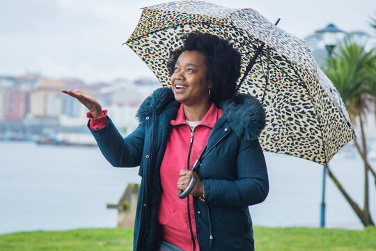 woman with umbrella on the street checking with her hand how the rain falls
