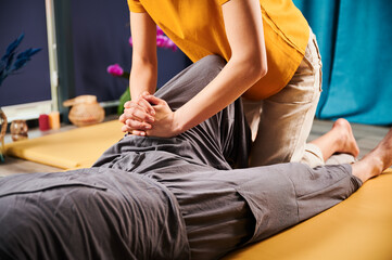 Masseuse making thai yoga massage. Cropped view of woman therapist doing traditional massage...