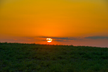 Sunset over fields and trees in a green hilly landscape under a colorful sky in sunlight in summer, Voeren, Limburg, Belgium, June, 2024