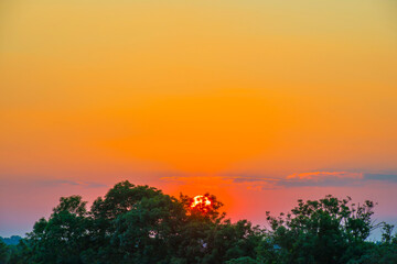 Sunset over fields and trees in a green hilly landscape under a colorful sky in sunlight in summer, Voeren, Limburg, Belgium, June, 2024