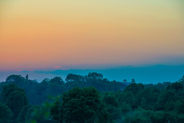 Sunset over fields and trees in a green hilly landscape under a colorful sky in sunlight in summer, Voeren, Limburg, Belgium, June, 2024