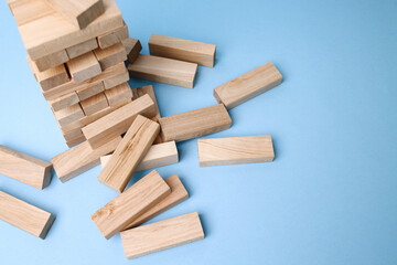 Stack of wooden block tower on blue blue background. Failure Business Concept. 