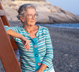 Attractive senior woman looking at the golden sunset at sea enjoying free time, vacation or retirement