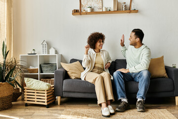 Obraz premium An African American couple sits on a couch in their home, communicating with sign language.