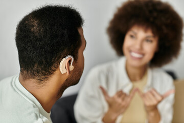 A young African American couple sits at home, communicating in sign language.