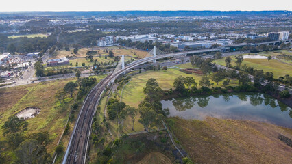 Aerial drone view of a train heading toward Rouse Hill Station on the metro northwest railway line,...