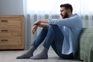 Loneliness concept. Sad man sitting on floor at home