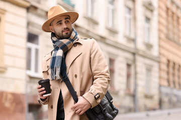 Handsome man in warm scarf with paper cup outdoors. Space for text