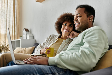 Alluring African American woman sitting near her husband with hearing aid and looking at laptop.