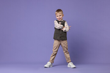 Happy little boy dancing on violet background. Space for text