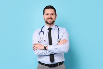 Smiling doctor with stethoscope on light blue background