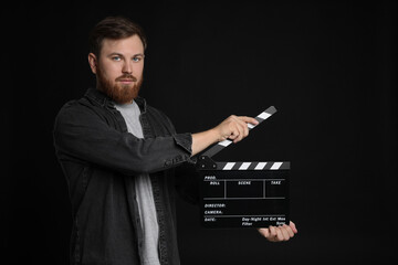 Making movie. Man with clapperboard on black background
