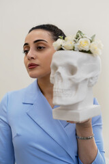 A cosmetologist showcases a skull decorated with flowers, merging concepts of life s fragility and...