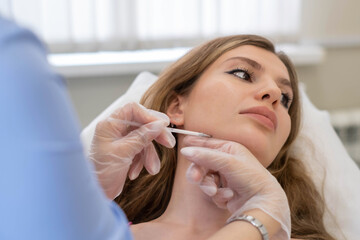 Aesthetician outlines strategic points on a woman s face, preparing meticulously for a series of...