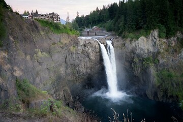 waterfall flowing over a cliff in front of hotel buildings in the mountains