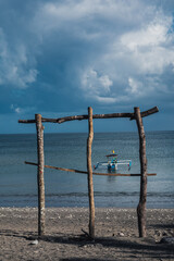 Small boat is moored on the sandy beach behind wooden branches