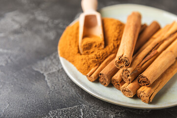 Ceylon cinnamon.Cinnamon sticks on a textured wooden background. Cinnamon roll and powder. Spicy...