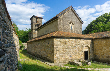 Fototapeta premium The back of the Church of St. George of the Ubisa Monastery. Stone walls, tiled roof, small door
