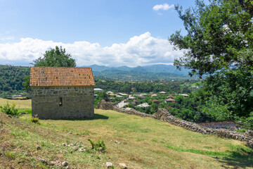 Back view of small church in the courtyard of Shorapani fortress. Village and mountains on the background