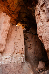 Cave with red rocks, small entrance, and a glowing light within