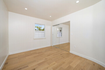 a bathroom is shown with white walls, hardwood flooring and a walk in closet