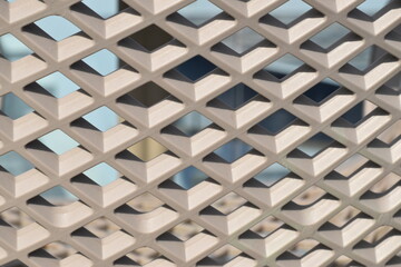Diamond-shaped cells of a brown plastic fence close-up.