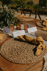 place settings sit on top of a wooden table for an outdoor dinner
