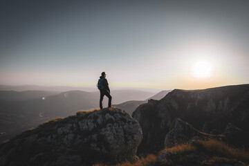 A man who hikers enjoys a break look at the top of the mountain at sunset adventure travel.