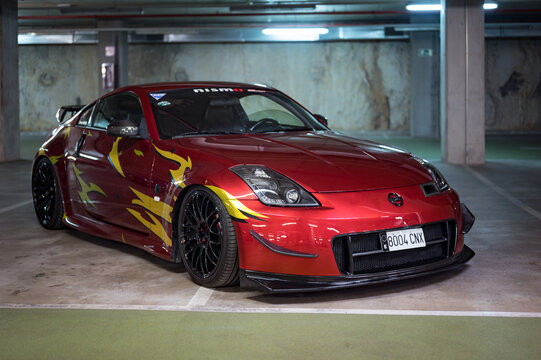 Japanese sports car tuned in the JDM style, the Nissan 350Z in red with yellow side vinyls