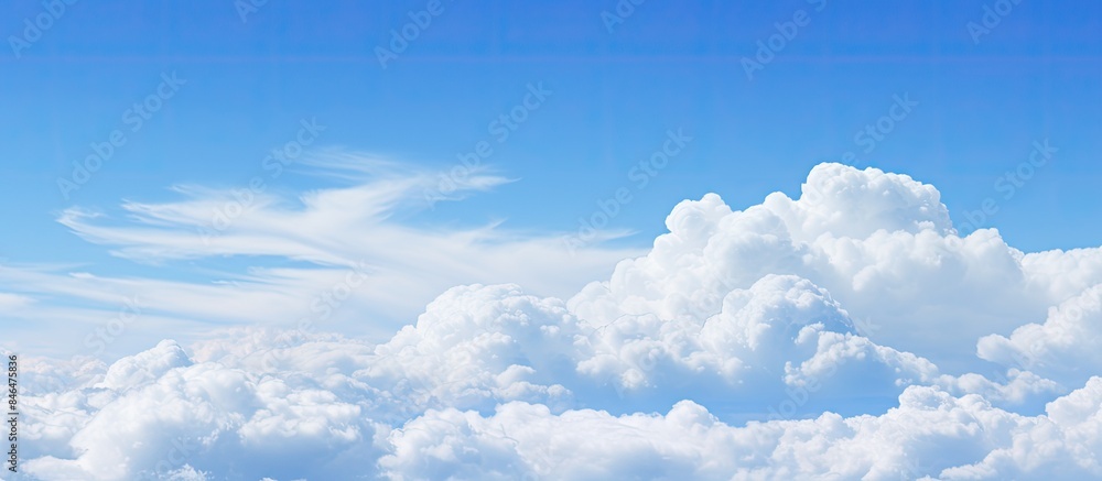 Poster Fluffy white clouds floating in a clear blue sky providing ample empty space for an image