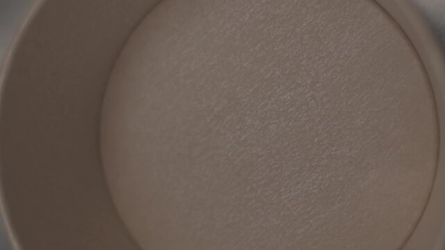Slow-motion top view of a cook filling in the bowl with mac and cheese.
