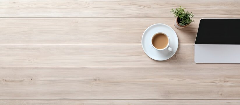 The office table is seen from above displaying a laptop a notepad and a cup of coffee There is enough free space for additional images or text