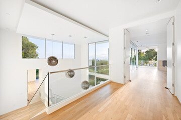 Long hallway with glass and white walls and floors leads to a modern house