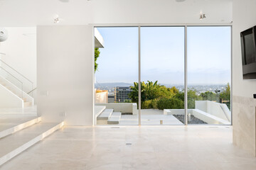 Fototapeta premium Contemporary white room beside sliding glass door with greenery view through the outdoor patio