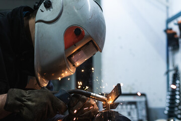 A man in protective helmet is working with piece of machinery