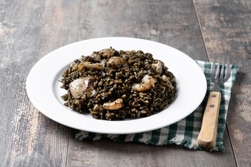 Black rice with seafood in plate on wooden table