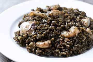 Black rice with seafood in plate on wooden table. Close up