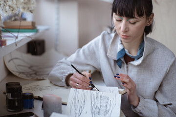 female artist look at her work drawing with pen and black ink. Graphic Painting. Creating modern Art