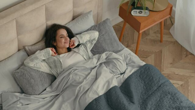 Top view woman waking up healthy sleep stretching approach window in pajamas cozy good morning at home inside vacations relax girl resting smiling wellbeing new day serene refresh energy bedroom bed