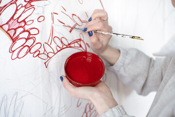 Female artist drawing painting with paint brush and red  paint. Graphic Painting. Creating modern Art