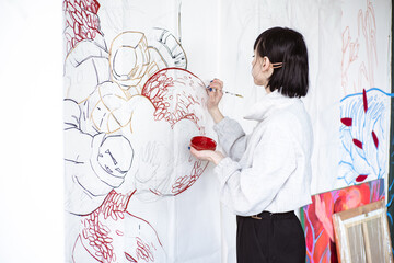Female artist drawing painting with paint brush and red  paint. Graphic Painting. Creating modern Art